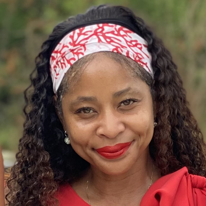 Picture of Latonia Chambers-Henry, founder of Value Financial Protection. African-American woman with long curly hair wearing a white and red headband, red top, and red lipstick, smiling outdoors with a blurred green background.