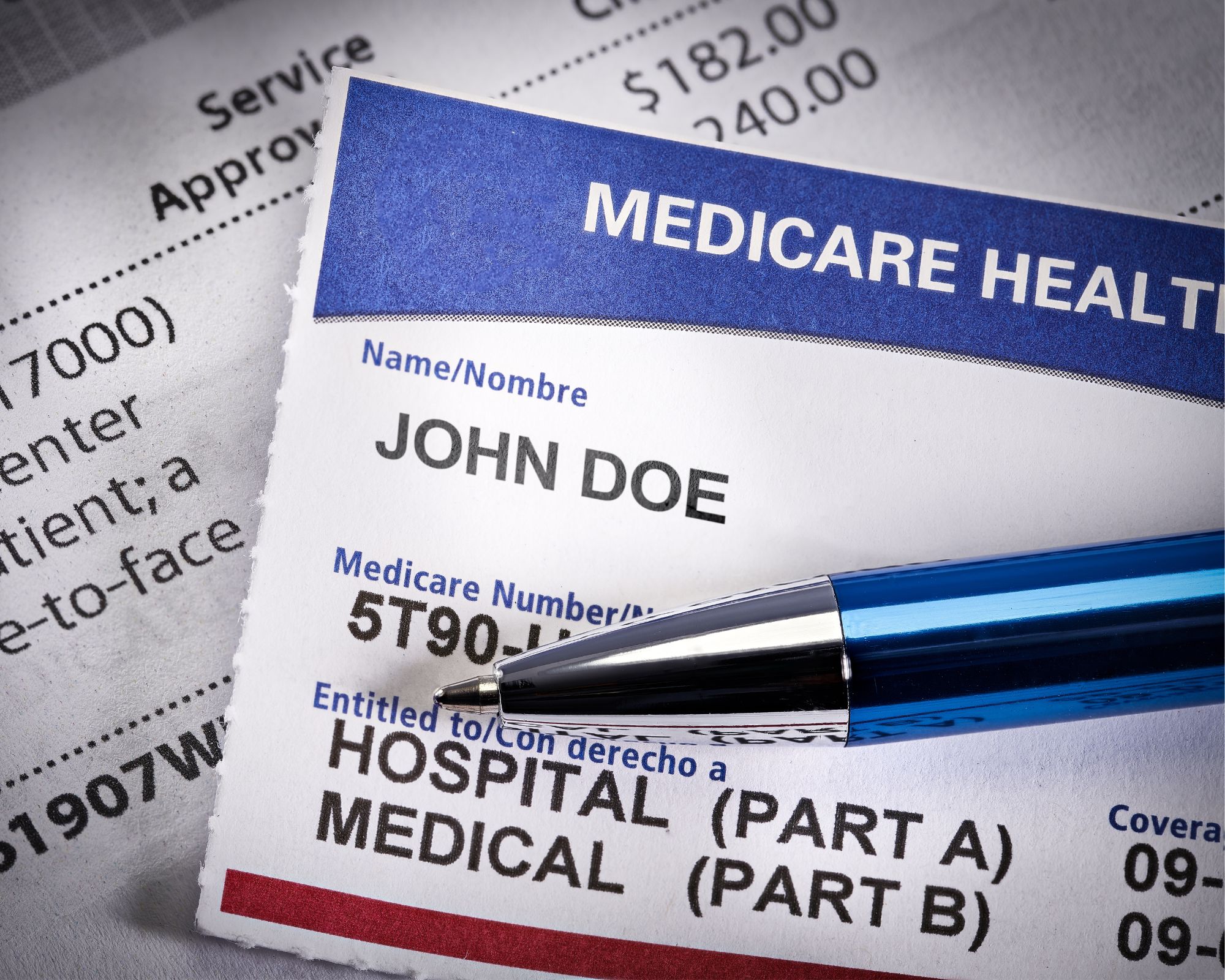 Close-up of a Medicare health insurance card with the name John Doe, a blue pen resting on it, and a medical bill in the background.