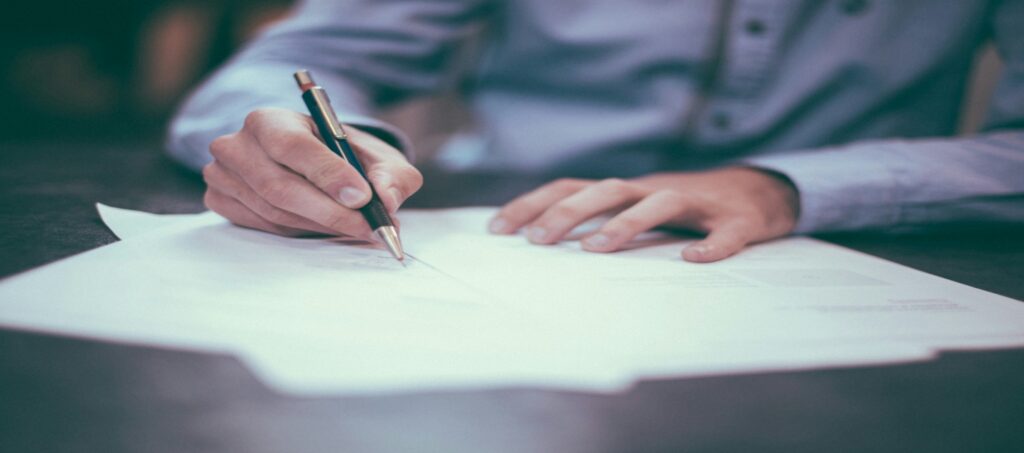 A person reviewing Medicare insurance coverage documents and paperwork at a wooden desk