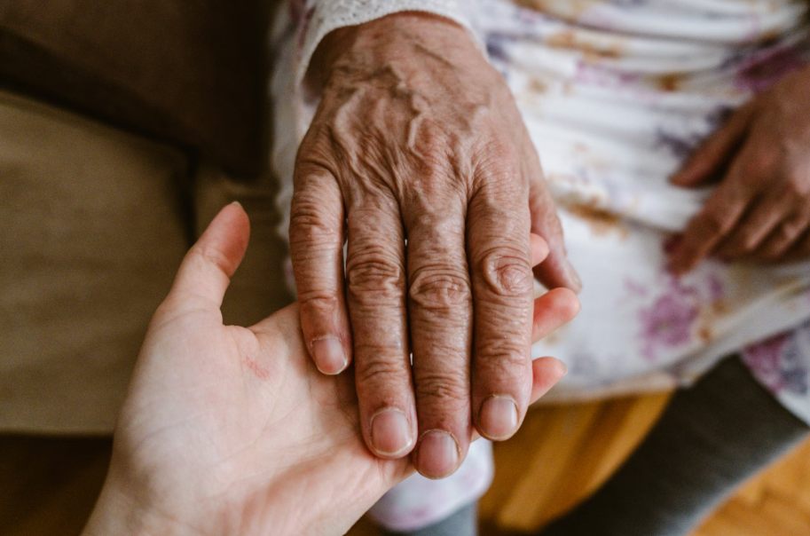 A person holding their senior parent’s hand.