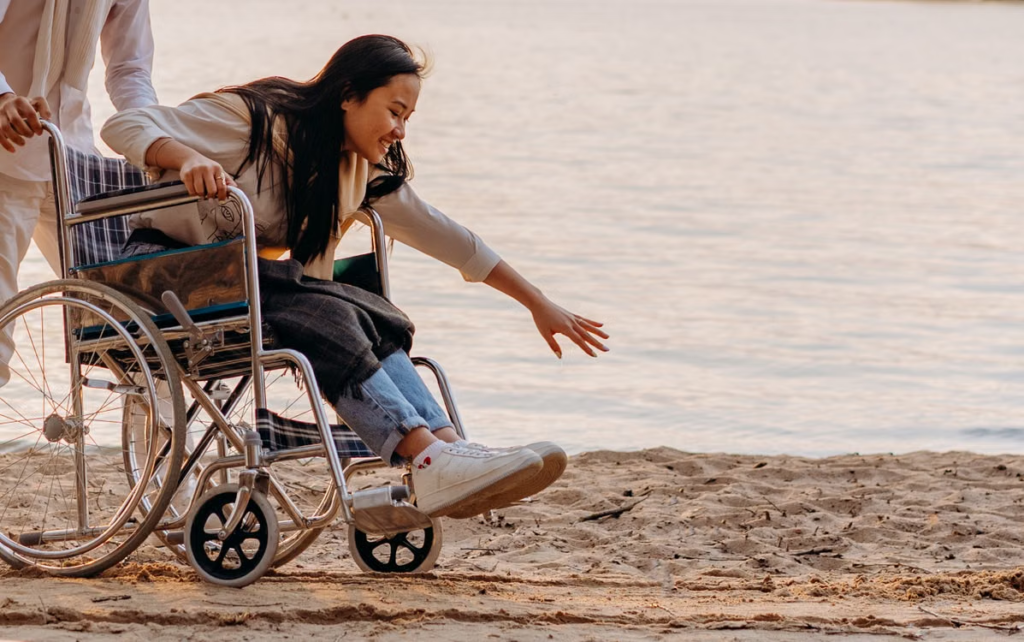 A person sitting in a wheelchair and reaching for sand 