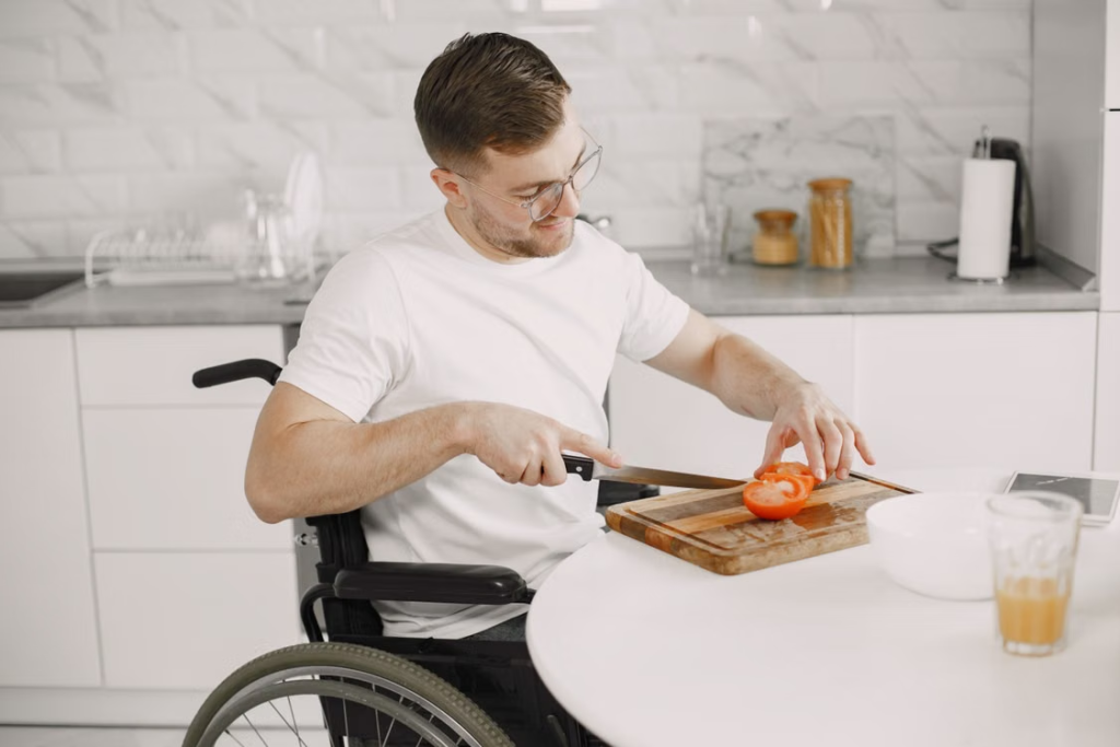 A person in a wheelchair slicing a tomato 