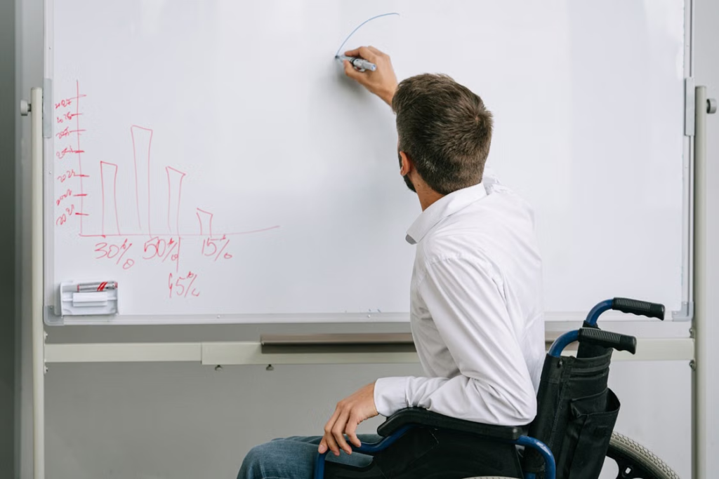A person in a wheelchair writing on a whiteboard 