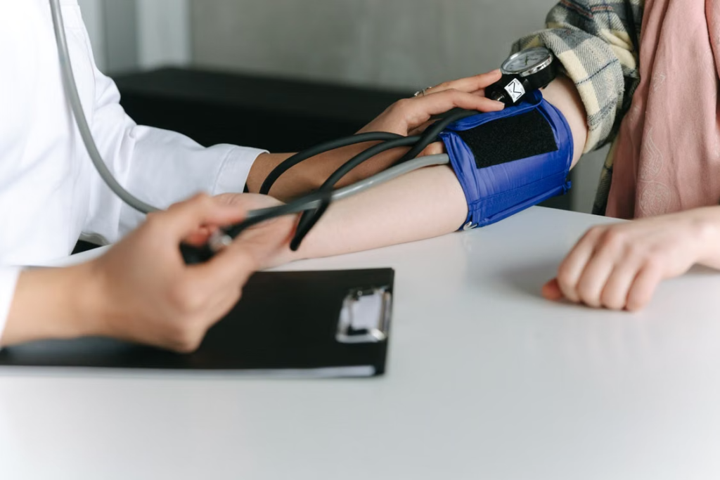 A healthcare worker using a sphygmomanometer to check a patient's blood pressure in a medical office