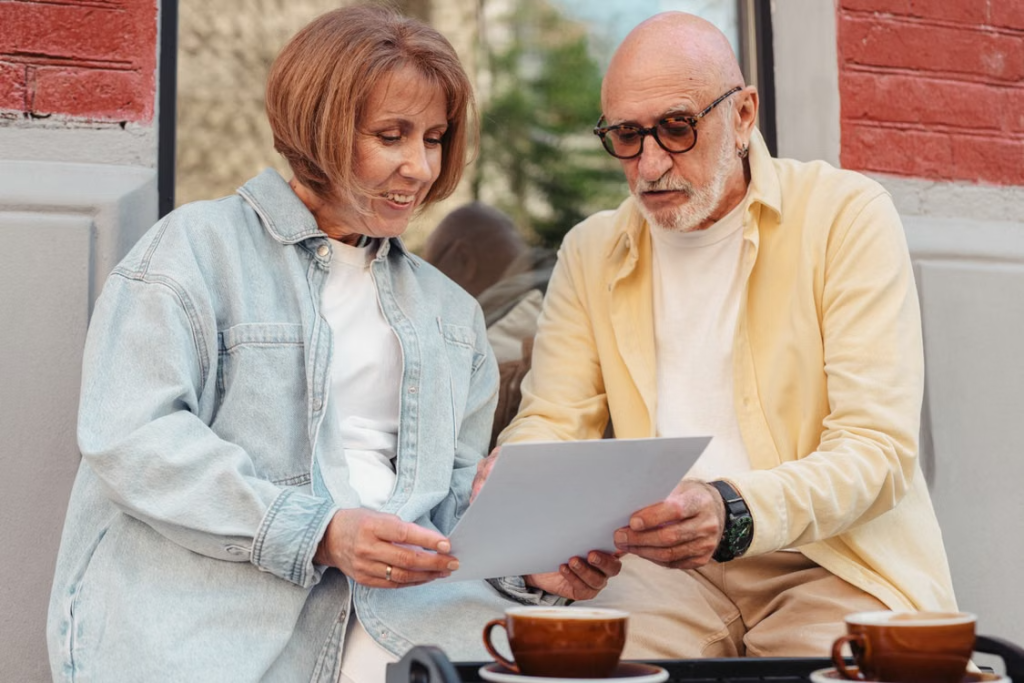 An older couple reading a document together at an outdoor cafe